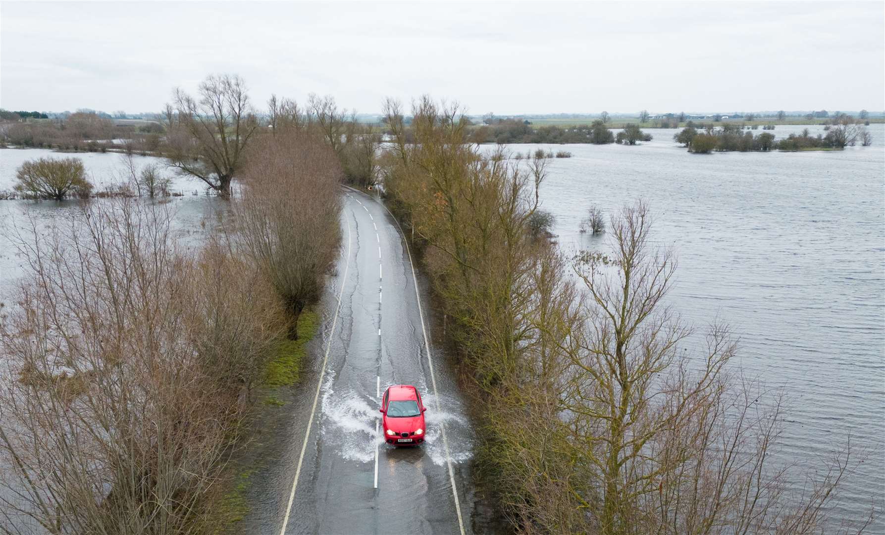 Cars make their way through surface water on the A1101 in Welney in Norfolk (Joe Giddens/PA)